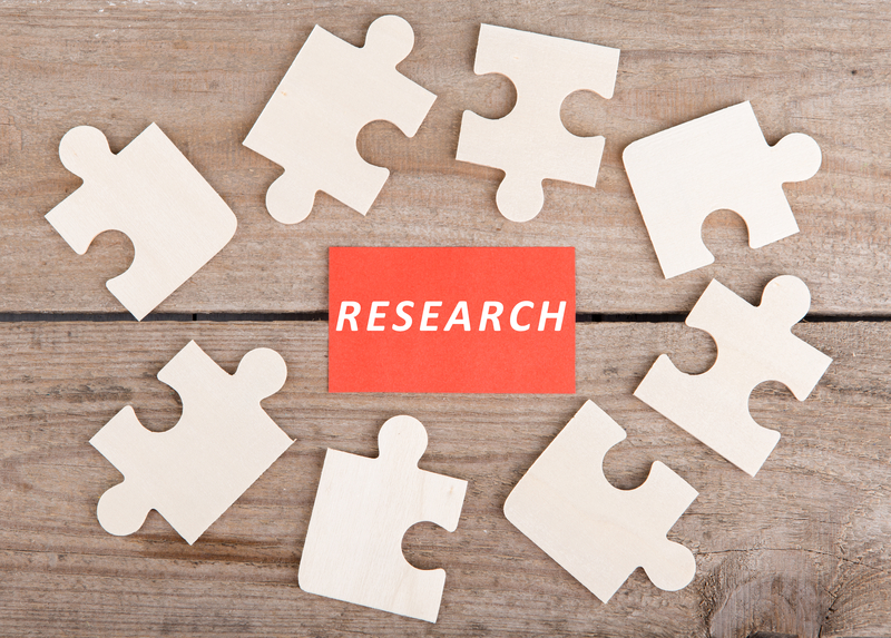Business Teamwork Concept - Jigsaw Puzzle Pieces with text "Research" on wooden background